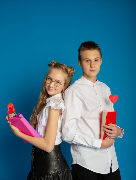 A couple of schoolchildren are teenagers on Valentine's Day on a blue background