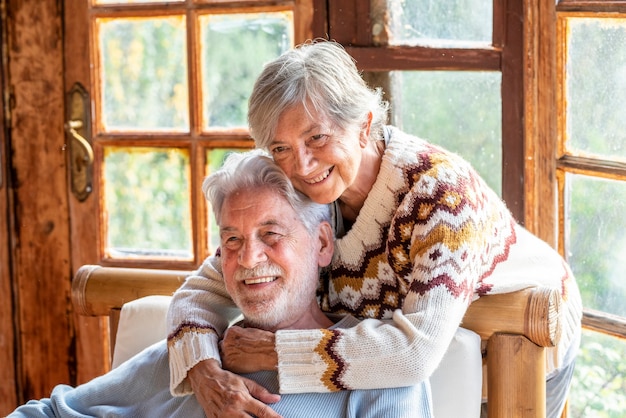 高齢の成熟した人々のカップルは、抱き合ったり愛したりして一緒に家で時間を楽しんでいます。恋に老人と老婆の肖像画。永遠の命と幸せな高齢者の概念
