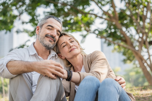 Couple seniors embracing and sitting in the park