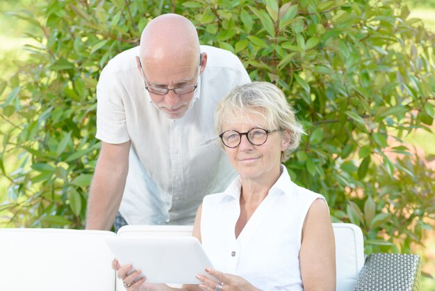 Пара пожилых людей смотрит на цифровой планшет