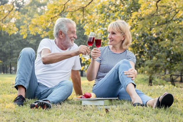 Couple seniors sipping wine fruity together with happy face.