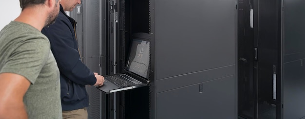 A couple of server engineers cooperate in high tech data centers. Technicians team updating hardware inspecting system performance in super computer server room or cryptocurrency mining farm.