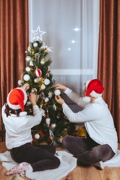 Couple shooting in front of decorated christmas tree copy space gift card