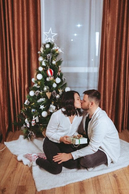 Couple shooting in front of decorated christmas tree copy space gift card