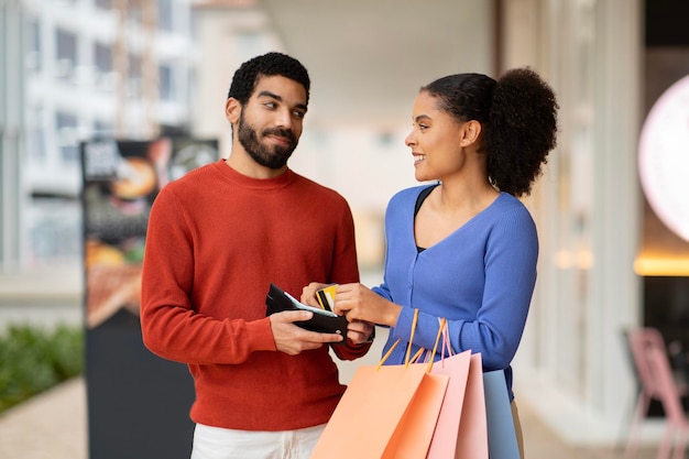 Foto marito di acquisto delle coppie che dà la carta di credito alla moglie al centro commerciale