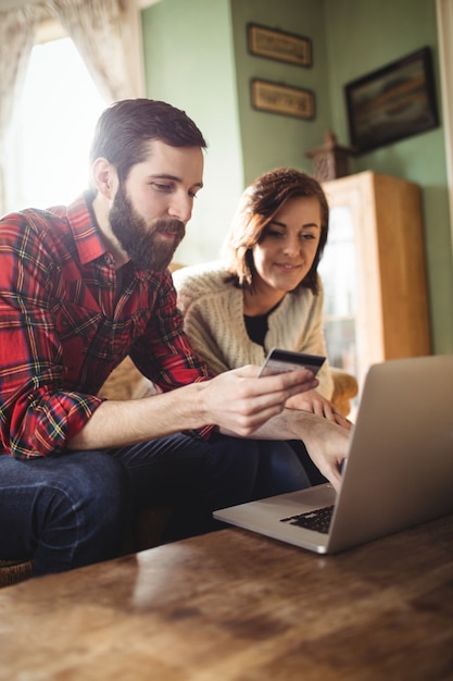 Couple shopping online on laptop in living room