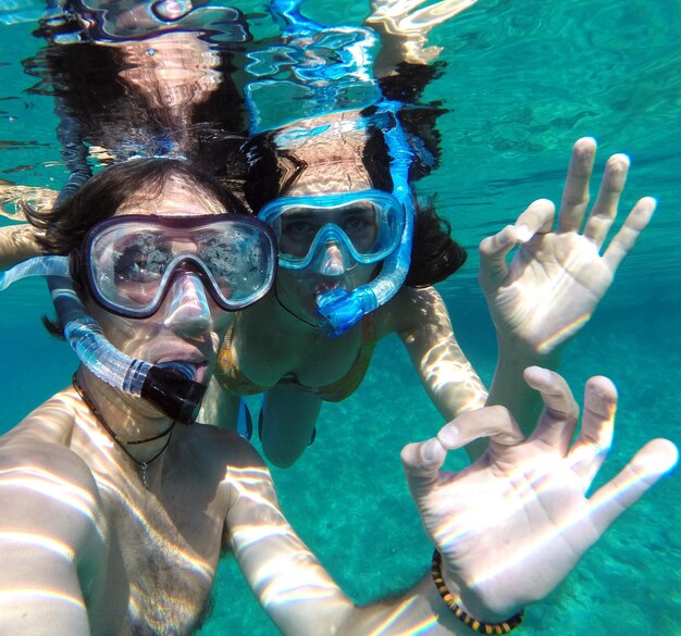 Couple showing ok sign while snorkeling in sea