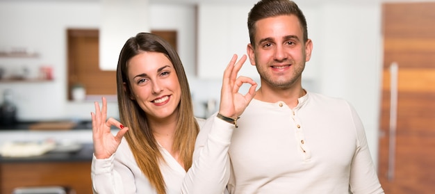 Couple showing an ok sign with fingers in a house