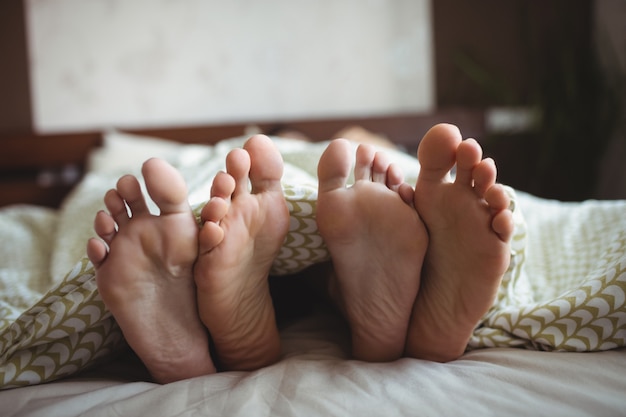 Couple showing their feet while lying on a bed