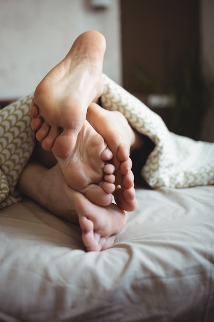 침대에 누워있는 동안 그들의 발을 보여주는 커플
