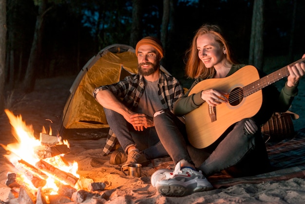 Couple singing by a tent with a campfire