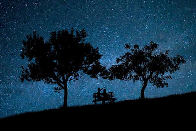 The couple sit on the bench against the background of the stars