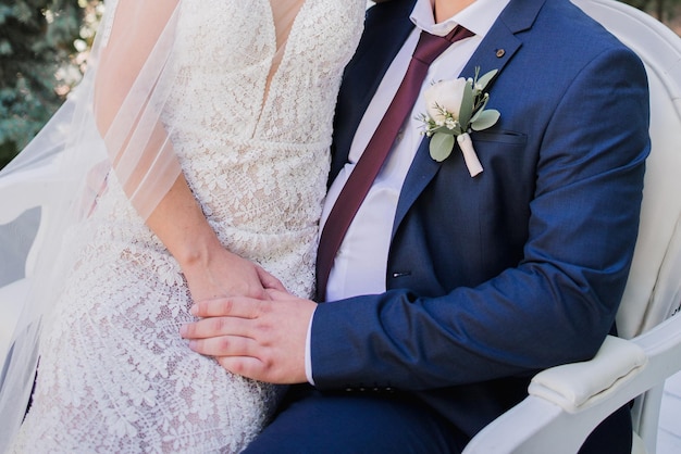 A couple sits on a bench in front of a white wall.