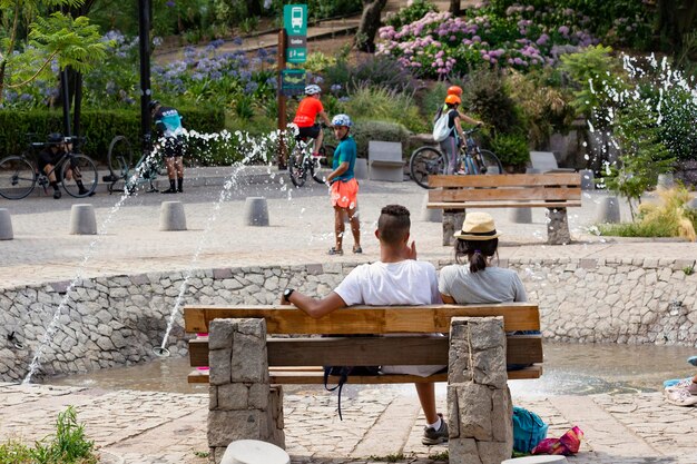 A couple sits on a bench in a park next to the fountain in Santiago Chile