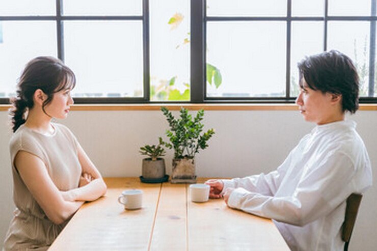 Photo 一对夫妇坐在桌子旁边,喝着一杯咖啡聊天