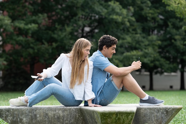 Couple sitting back to back and girl spying phone