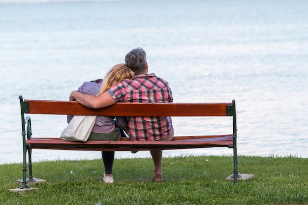 Foto coppia seduta su una panchina in posa romantica