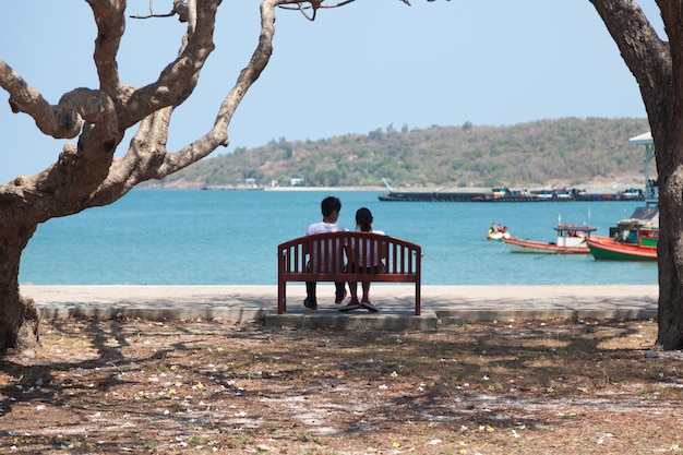 Couple sitting on a bench under a tree.