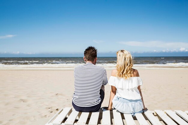 Couple sitting on boardwalk on the beach