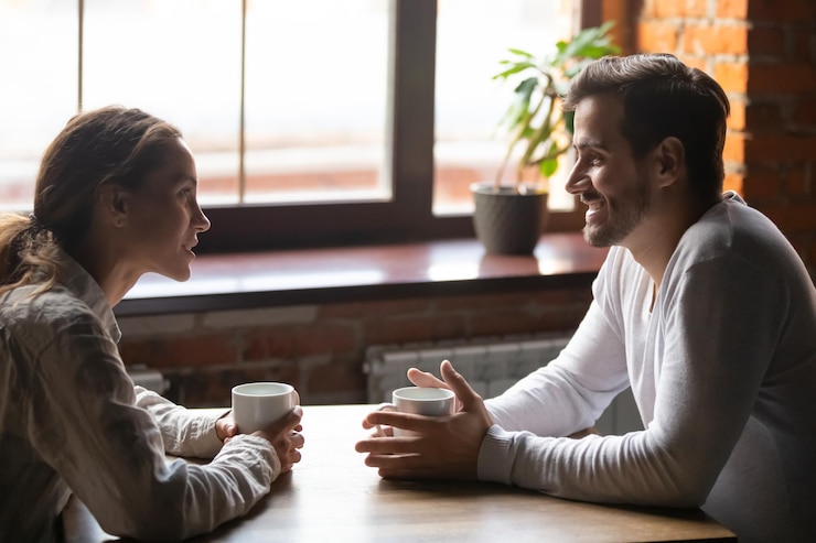 Photo couple sitting in cafe talking drinking tea or coffee