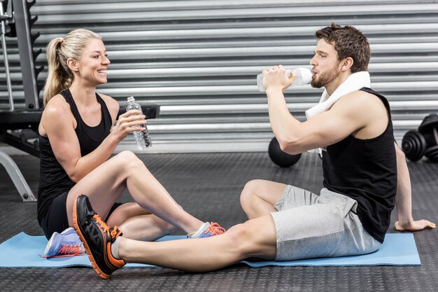 Coppie che si siedono sulla stuoia di forma fisica alla palestra del crossfit