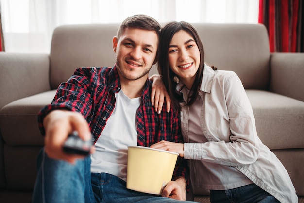 Couple sitting on the floor hugs and watch movie