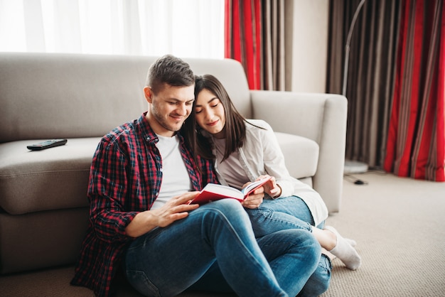 Couple sitting on floor and looks at book together