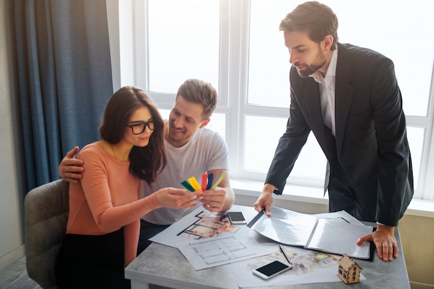 Couple sitting in front of realtor and choosing apartment plan