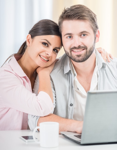 Couple sitting at home and using laptop together.