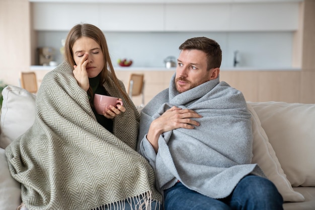 Couple sitting at home wrapped in plaids feeling unwell ill seasonal epidemic viruses influenza