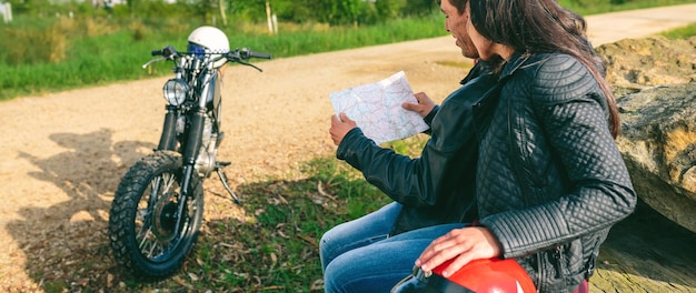 Couple sitting looking at a map with motorcycle