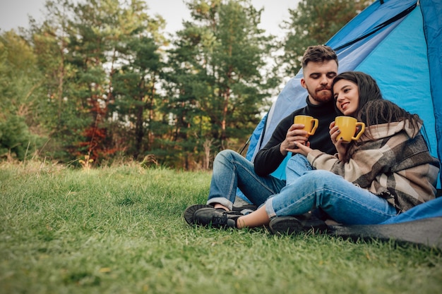 Couple sitting near tent with cups