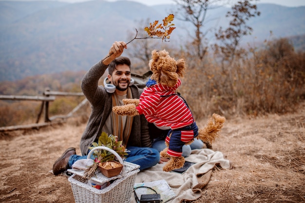 写真 ピクニックで毛布の上に座っているカップル。犬と遊ぶ人。