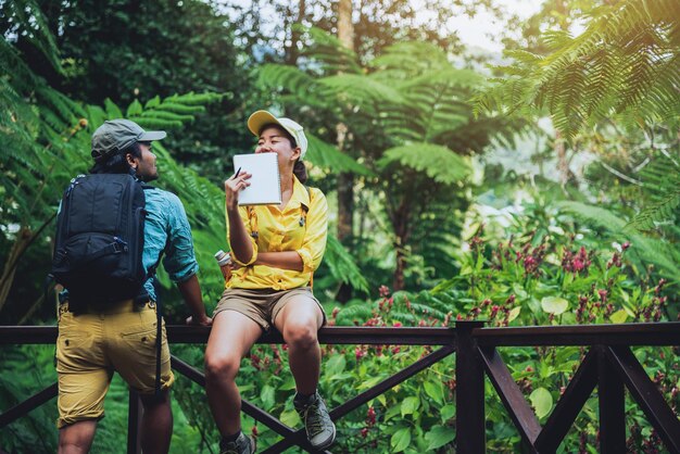 写真 森の木の反対側のレールに座っているカップル