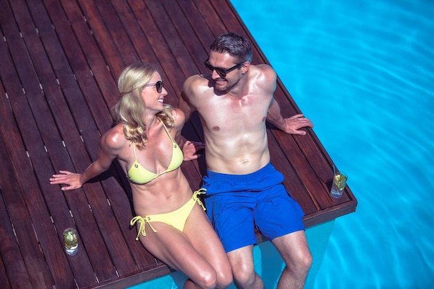 Couple sitting at poolside with glass of mojito