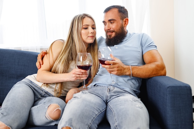 Couple sitting on sofa at home and drinking wine