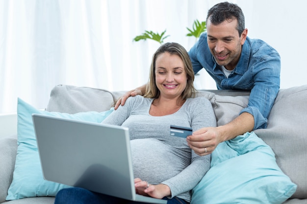 Couple sitting on the sofa and shopping online with a credit card