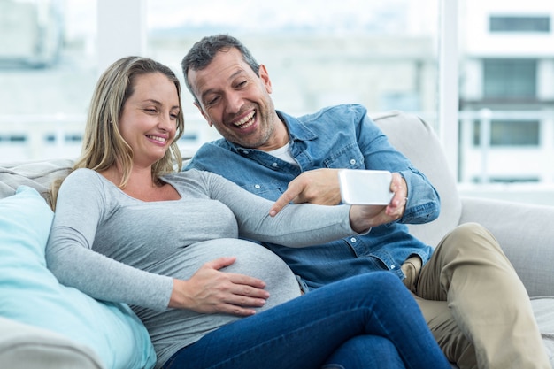 Couple sitting on sofa and taking a selfie on smartphone