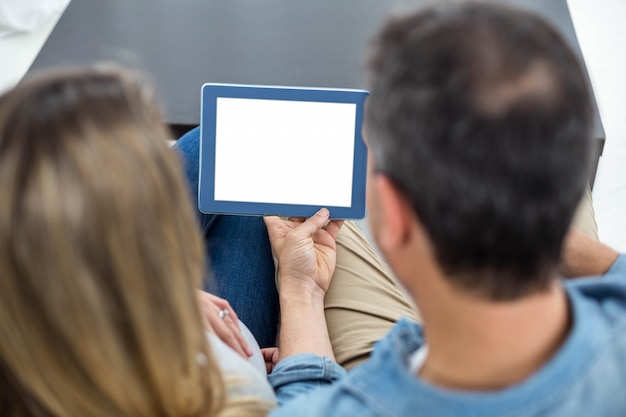 Couple sitting on sofa and using digital tablet