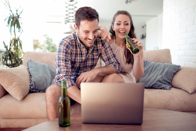 Couple sitting on sofa and using laptop in living room