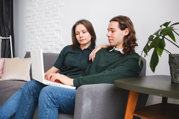 Photo couple sitting on the sofa with notebook and phone man and woman communicating on the laptop phone