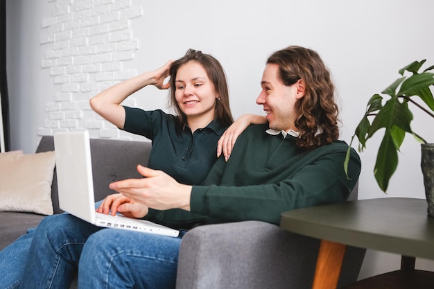 Couple sitting on the sofa with notebook and phone Man and woman communicating on the laptop phone