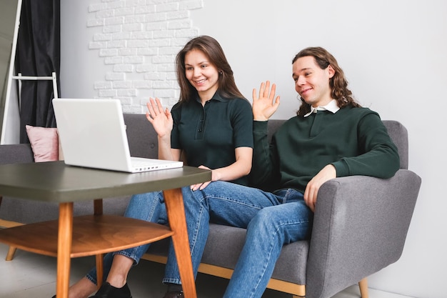 Couple sitting on the sofa with notebook and phone Man and woman communicating on the laptop phone