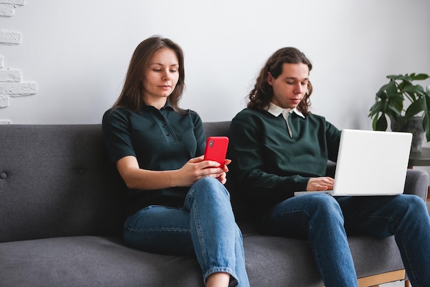 Photo couple sitting on the sofa with notebook and phone man and woman communicating on the laptop phone