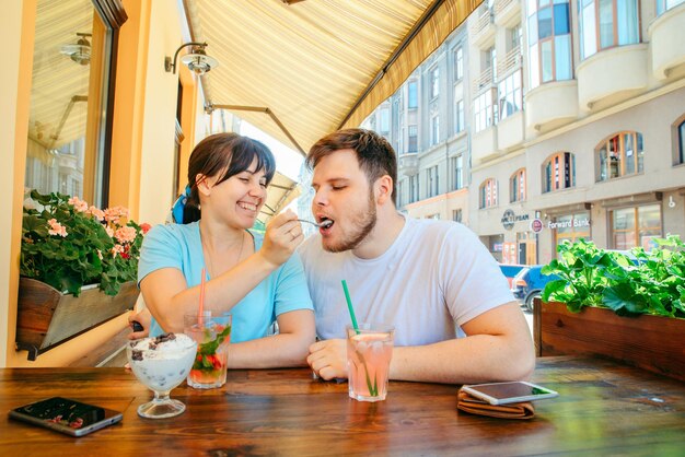 Couple sitting in summer cafe drinking cool drinks and talking