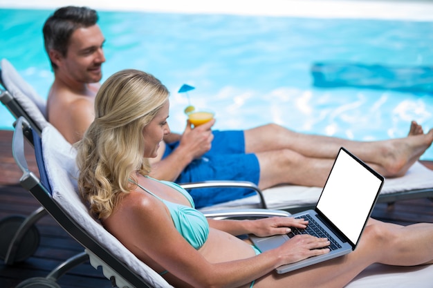 Couple sitting on sun lounger near pool