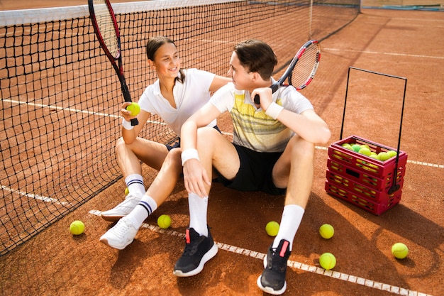 Couple sitting on tennis court