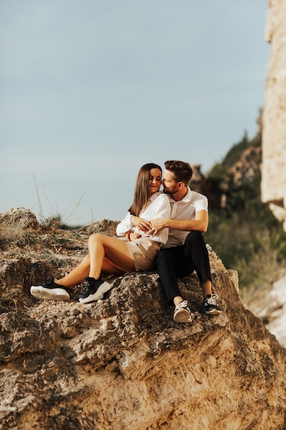 A couple sitting together on the rocks at the mountains.