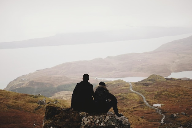 Photo couple sitting on top of rock