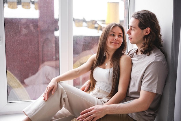 Couple sitting on the windowsill Couple looking out the window Couple in love